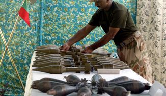 A Pakistani soldier arranges weapons reportedly recovered from hideouts of militants in tribal areas as the weapons are displayed in Peshawar, Pakistan, on Wednesday, Aug. 29, 2012. (AP Photo/Mohammad Sajjad)