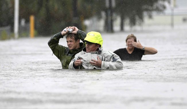 Chuck Cropp (center), his son, Piers (left), and wife, Liz, wade through floodwaters from Hurricane Isaac on Aug. 29, 2012, in New Orleans. (Associated Press)