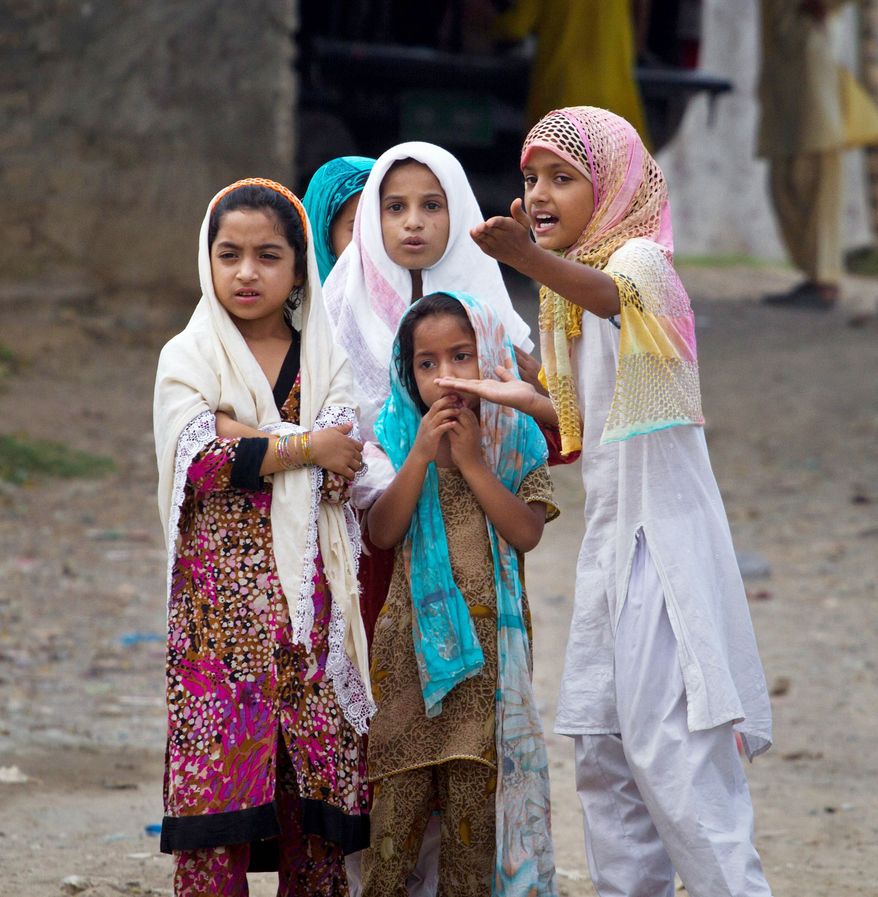Pakistani Muslim girls talk about press gathered outside a mosque, unseen, where police arrested a Muslim cleric Khalid Chishti, in a suburb of Islamabad, Pakistan, Sunday, Sept. 2, 2012. In the latest twist in a religiously charged case that has focused attention on the country's harsh blasphemy laws, Pakistani police arrested Chishti who they say planted evidence in the case of a Christian girl accused of blasphemy. (AP Photo/Anjum Naveed)