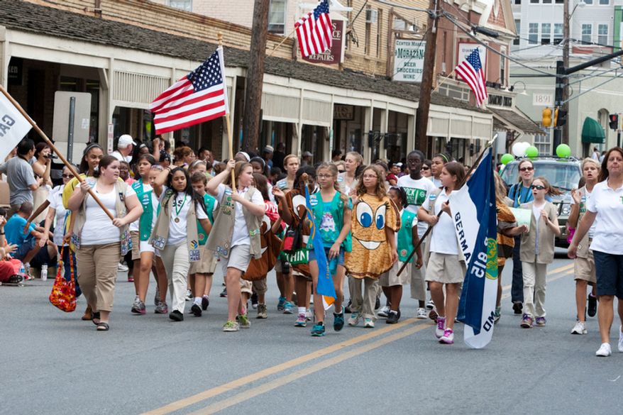 ** FILE ** Girl Scouts wave the flag while participating in the Labor Day parade in Gaithersburg, Md., in 2012. (The Washington Times)