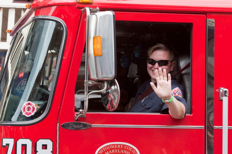 A firefighter waves from a firetruck during the Labor Day parade in Gaithersburg, Maryland. (Craig Bisacre/The Washington Times)