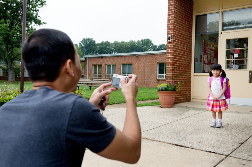 Stephan Mai, left, photographs Sarah, 5, on her first day of kindergarden at North Springfield Elementary School. (Andrew Harnik/The Washington Times)
