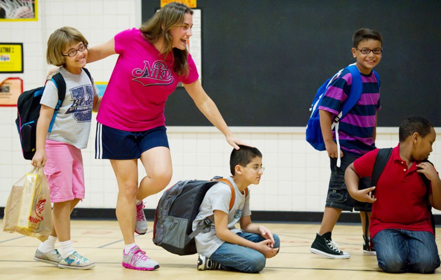 P.E. teacher Sue Metz, second from left, gets students excited for their first day back to school. (Andrew Harnik/The Washington Times)