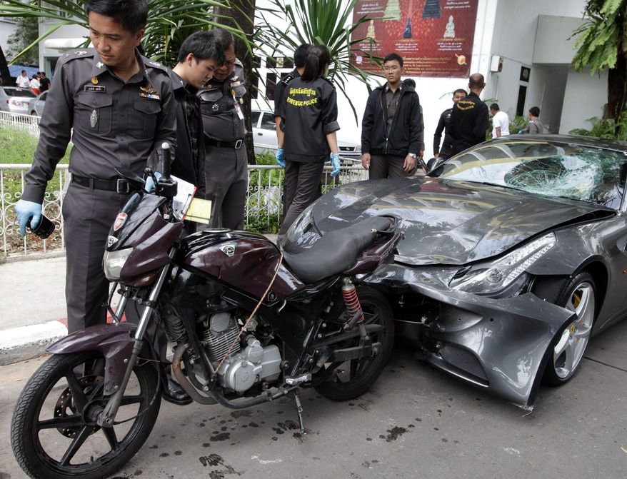 Thai police officers inspect a motorcycle and a Ferrari involved in a hit-and-run accident during an investigation at Thong Lor police station in Bangkok on Monday. A grandson of the creator of the Red Bull energy drink has been arrested for driving the Ferrari that struck a police officer and dragged his dead body down a Bangkok street in a hit-and-run. (Associated Press)