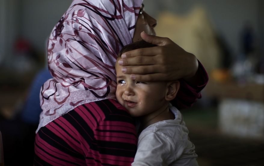 Amjad Al-Saleh, a Syrian child suffering from food poisoning, is comforted by his mother as they take refuge at the Bab Al-Salameh border crossing near Azaz, Syria, on Wednesday, Sept. 5, 2012, in hopes of entering a refugee camp in Turkey. The Al-Saleh family left their home in Marea, Syria, 11 days before when government forces shelled their house. (AP Photo/Muhammed Muheisen)