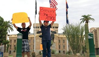Joshua Montano, left, and Francisco Luna protest in front of the Capitol the day after Arizona Gov. Jan Brewer, in an executive order reaffirming Arizona state law denying young illegal immigrants driver&#39;s licenses and other public benefits on Thursday, Aug. 16, 2012, in Phoenix. Brewer&#39;s order says she&#39;s reaffirming the intent of current Arizona law denying taxpayer-funded public benefits and state identification to illegal immigrants. (AP Photo/Ross D. Franklin)