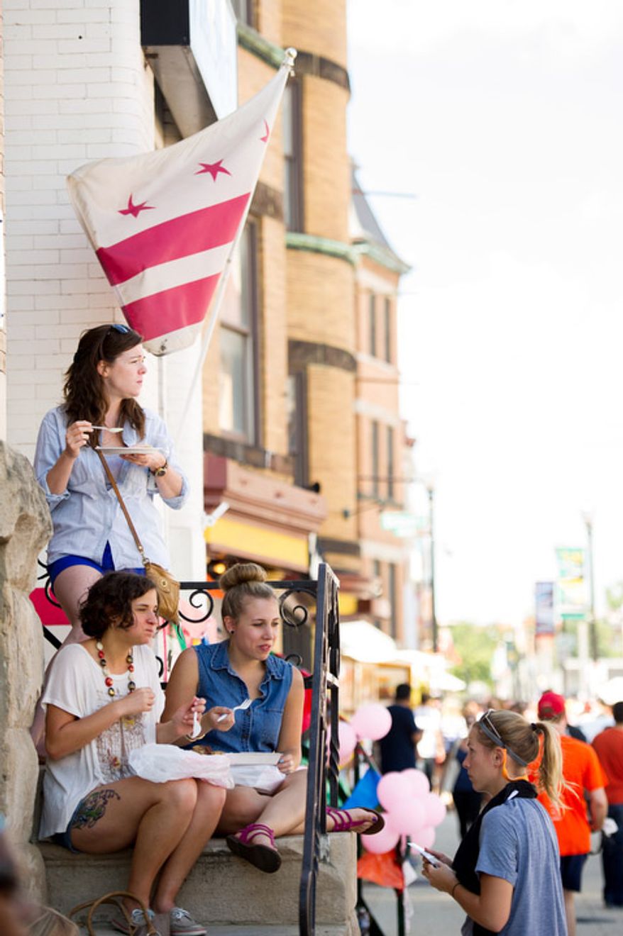 Casey Naughton of Washington, D.C., top left, and others sit on stoops along 18th street. (Andrew Harnik/The Washington Times)