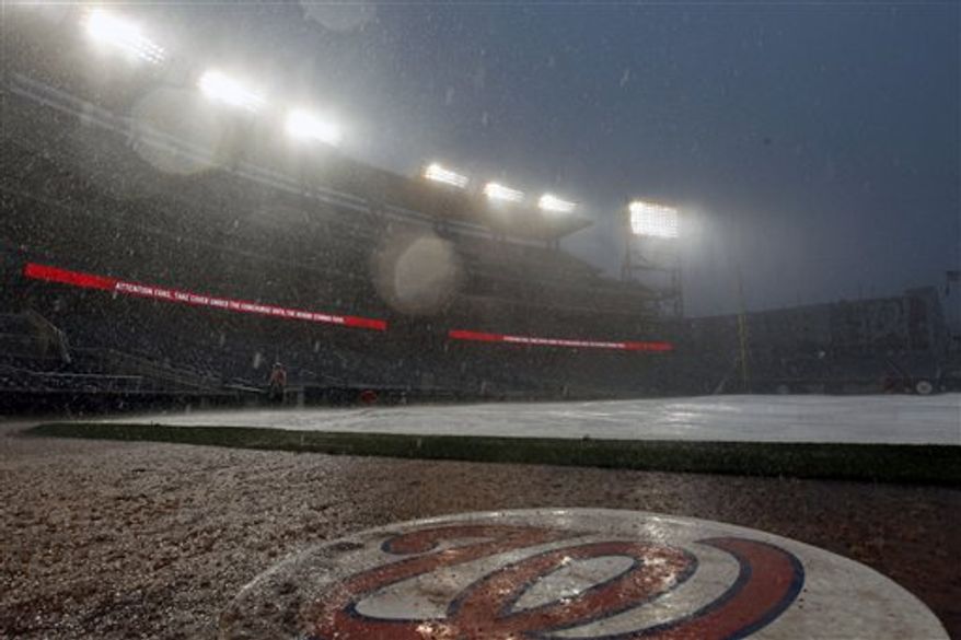 The tarp is on the field during a rain delay during the ninth inning of a baseball game between the Miami Marlins and the Washington Nationals at Nationals Park, Saturday, Sept. 8, 2012, in Washington. (AP Photo/Alex Brandon)