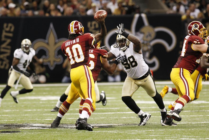 Washington Redskins quarterback Robert Griffin III (10) passes as New Orleans Saints defensive tackle Sedrick Ellis (98) rushes in the second half of an NFL football game at the Mercedes-Benz Superdome in New Orleans, Sunday, Sept. 9, 2012. (AP Photo/Bill Haber)