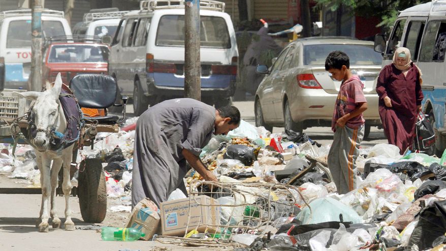 A second-hand dealer searches for valuables in loads of garbage on a Cairo street. A government revamping of trash collection flopped and metal trash bins proved to be easy prey for thieves. (Associated Press)