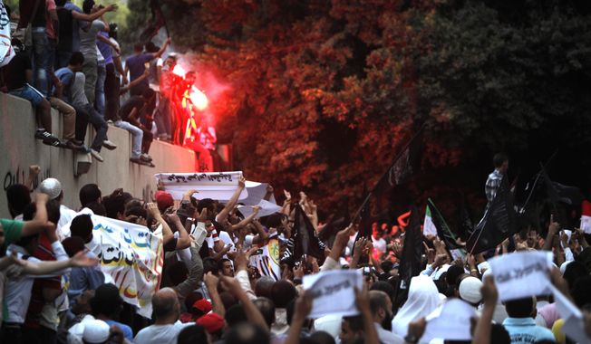 **FILE** Egyptian protesters climb the walls of the U.S. Embassy in Cairo on Sept. 11, 2012. The protesters, largely ultraconservative Islamists, went into the courtyard and brought down the U.S. flag, replacing it with a black flag with Islamic inscription, in protest of a film deemed offensive of Islam. (Associated Press)