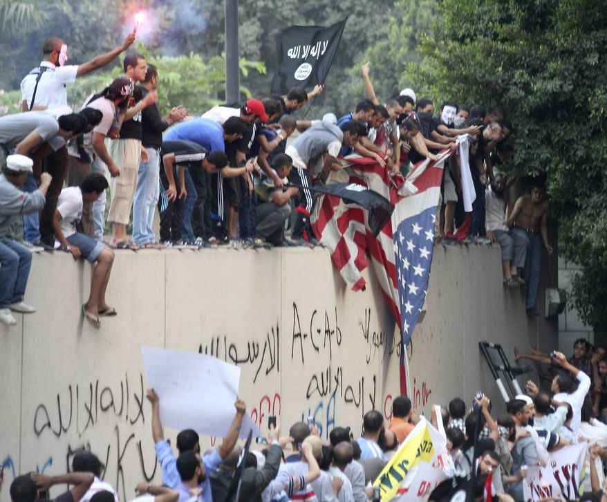 Protesters destroy an American flag pulled down from the U.S. embassy in Cairo on Sept. 11, 2012. The protesters, largely ultraconservative Islamists, climbed the walls of the embassy, went into the courtyard and brought down the flag, replacing it with a black flag with Islamic inscription, in protest of a film deemed offensive of Islam. (Associated Press)
