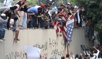 Protesters destroy an American flag pulled down from the U.S. embassy in Cairo, Egypt, Tuesday, Sept. 11, 2012. Egyptian protesters, largely ultra conservative Islamists, climbed the walls of the U.S. embassy in Cairo, went into the courtyard and brought down the flag, replacing it with a black flag with Islamic inscription, in protest of a film deemed offensive of Islam. (AP Photo/Mohammed Abu Zaid)