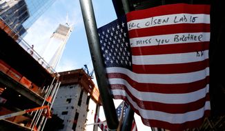 A message is written on a United States flag at the construction site of One World Trade Center in the background during the 11th anniversary of the Sept. 11 terrorist attacks. (Associated Press)