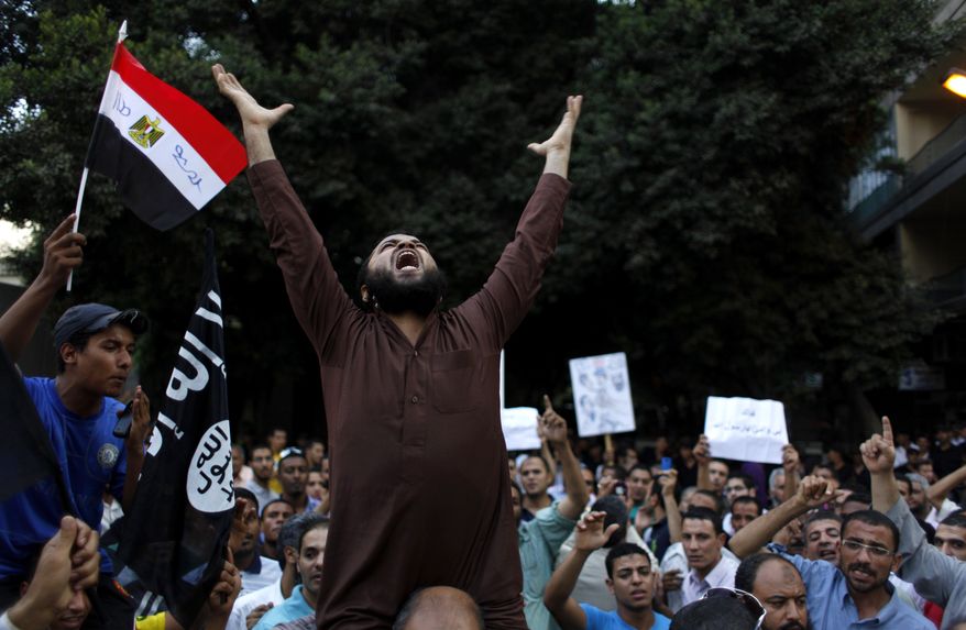 Egyptian protesters carry their national flag and a flag with Arabic that reads "No God but Allah, and Mohammed is his prophet," and chant anti-U.S. slogans during a demonstration in front of the U.S. Embassy in Cairo on Sept. 12, 2012, as part of widespread anger across the Muslim world about a film ridiculing Islam's prophet Muhammad. (Associated Press)