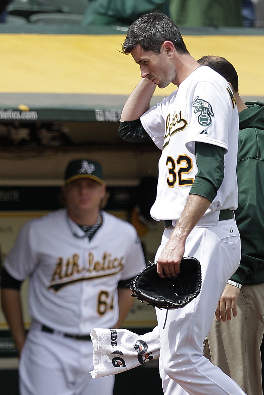 In this photo from Wednesday, Sept. 5, 2012, Oakland Athletics pitcher Brandon McCarthy (32) places his hand to his head as he leaves the baseball game against the Los Angeles Angels in Oakland, Calif. McCarthy remains in a ''life-threatening'' situation in a Bay Area hospital two days after being hit in the head by a line drive. Struck on the right side of his head by a hard shot from the Angels' Erick Aybar, McCarthy suffered an epidural hemorrhage, brain contusion and skull fracture. He had two hours of surgery to relieve pressure on his brain late Wednesday night. A's athletic trainer Nick Paparesta was asked Friday if McCarthy was still in a life-threatening situation. "Absolutely he is. It's brain surgery,'' Paparesta said. ''It's life-threatening. At any possible moment something could go wrong, he could have a complication. Absolutely.'' (AP Photo/Ben Margot)