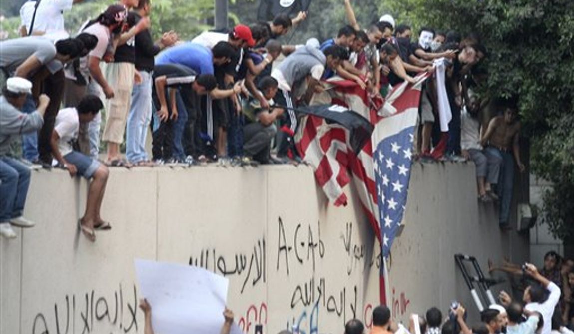 Protesters destroy an American flag pulled down from the U.S. embassy in Cairo, Egypt, Tuesday, Sept. 11, 2012. Egyptian protesters, largely ultra conservative Islamists, have climbed the walls of the U.S. embassy in Cairo, went into the courtyard and brought down the flag, replacing it with a black flag with Islamic inscription, in protest of a film deemed offensive of Islam. (AP Photo/Mohammed Abu Zaid)