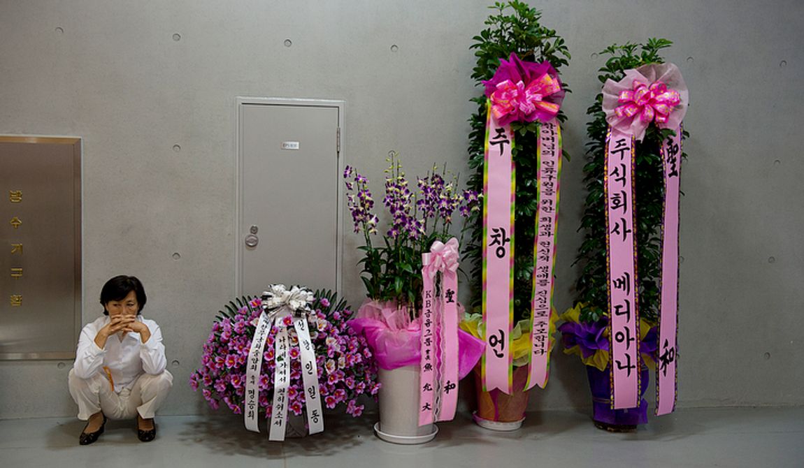 A mourner sits down near several flower arrangements at the Cheongpyeong Heaven and Earth Training Center complex near Seoul, Korea on Wednesday, Sept. 12, 2012. Although the announcement of the death of Unification Church founder Rev. Sun Myung Moon asked for no flowers, hundreds of these tribute flowers have poured into the complex over the last week.  (Barbara L. Salisbury/The Washington Times)