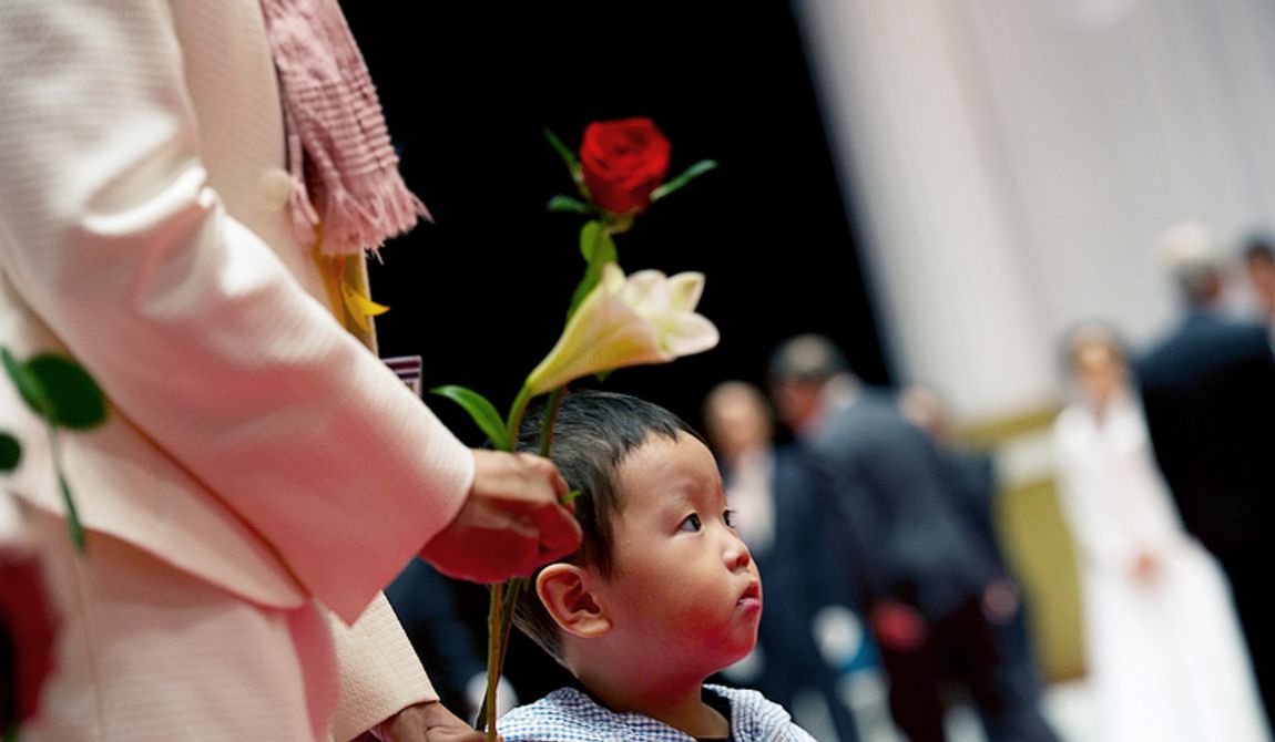 A young boy waits with his mother to place flowers on a table inside the Cheongpyeong Heaven and Earth Training Center complex outside of Seoul, Korea on Wednesday, Sept. 12, 2012 to honor the Rev. Sun Myung Moon. Mourners placed flowers (roses for the father and lilies for the mother) on a table and then bowed before family members. (Barbara L. Salisbury/The Washington Times)