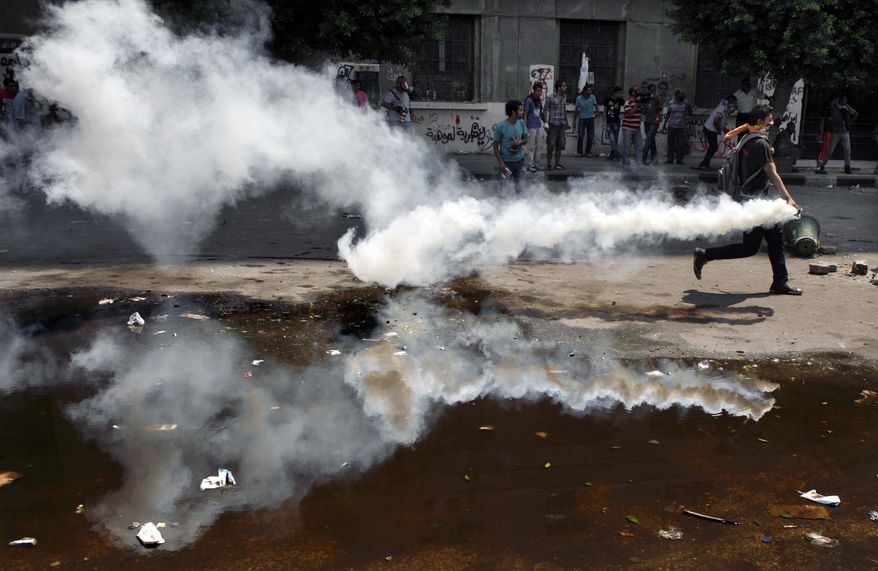 An Egyptian protester throws back a tear gas canister toward riot police, unseen, during clashes outside the U.S. embassy in Cairo, Egypt, Thursday, Sept. 13, 2012. Protesters clash with police near the U.S. Embassy in Cairo for the third day in a row. Police used tear gas to disperse the demonstrators and the two sides pelted each other with rocks. (AP Photo/Nasser Nasser)