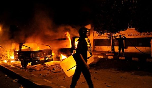 A riot policeman passes a burning vehicle during clashes outside the U.S. embassy in Cairo early Thursday, Sept. 13, 2012, as part of widespread anger across the Muslim world about a film ridiculing Islam&#39;s Prophet Muhammad. (Associated Press)