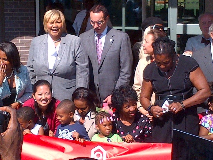 D.C. dignitaries joined city children on Thursday to cut the ribbon in front of Educare, a state-of-the-art center focusing on early childhood education in Ward 7. From left, are D.C. Housing Authority Director Adrianne Todman, council member Yvette M. Alexander, Ward 7 Democrat, and Mayor Vincent C. Gray. Dorothy Douglas, leaning over the banner in the black dress, is a member of the D.C. State Board of Education for Ward 7. (Tom Howell Jr./The Washington Times)