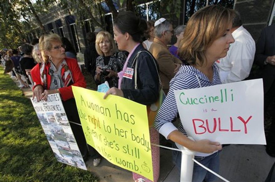 Protesters hold signs as they wait for the Virginia Board of Health meeting on abortion clinic regulations in Richmond, Va., Friday, Sept. 14, 2012. Activists on both sides of the abortion issue have gathered outside the meeting and the board was scheduled to take comments before voting on the regulations Friday. (AP Photo/Steve Helber)