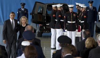 President Obama and Secretary of State Hillary Rodham Clinton walk Sept. 14, 2012, back to their seats after speaking during a ceremony at Andrews Air Force Base, Md., marking the return to the United States of the remains of the four Americans killed earlier in the week in Benghazi, Libya. Behind them at right is one of the flag draped transfer cases of the remains of the four Americans killed this week in Benghazi, Libya. (Associated Press)