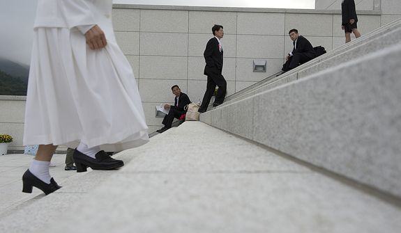 Mourners make their way up the steps while others rest on them, heading to the Seonghwa, or ascension, ceremony, known as the traditional funeral in western terms, for the late Rev. Sun Myung Moon on Saturday, Sept. 15, 2012 at the Cheong Shim Peace World Center in Gapyeong, Korea. Thousands of mourners from countries around the world came to witness the event and say goodbye to the head of the Unification Church. Some 15,000 fit into the stadium, where the funeral was held, with another 10,000 to 15,000 expected to be watching live simulcasts around the complex. Because it was first-come, first-served for many of the seats, most mourners arrived early and spent time outside on the steps. (Barbara L. Salisbury/The Washington Times)