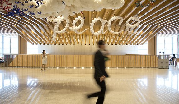 People walk through a hallway past a &quot;peace&quot; sign that is meant to look like clouds at the Cheong Shim Peace World Center in Gapyeong, Korea on Saturday, Sept. 15, 2012, the day of the late Rev. Sun Myung Moon&#x27;s funeral. (Barbara L. Salisbury/The Washington Times)