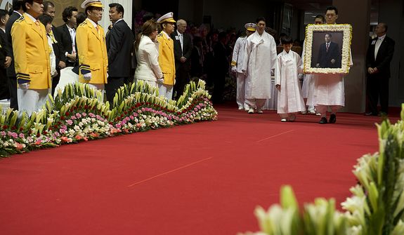 Grandson Shin Jun, left, and Kwon Jin Moon, one of the sons of the late Rev. Sun Myung Moon, carry in a portrait of the reverend at the beginning of the Seonghwa, or ascension, ceremony, known as the traditional funeral in western terms, Saturday, Sept. 15, 2012 at the Cheong Shim Peace World Center in Gapyeong, Korea. At left in yellow are members of second-generation Unification Church families. (Barbara L. Salisbury/The Washington Times)