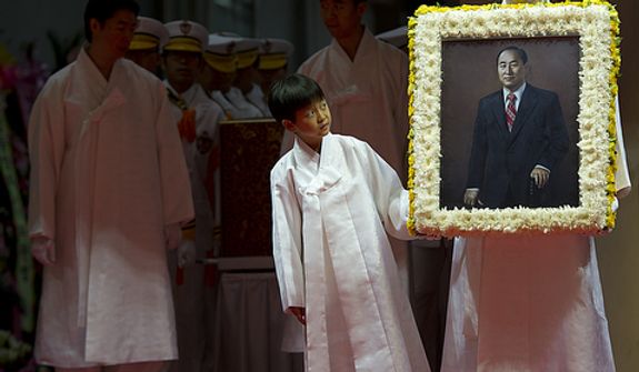 Grandson Shin Jun, left, and Kwon Jin Moon, one of the sons of the late Rev. Sun Myung Moon, carry in a portrait of the reverend at the beginning of the Seonghwa, or ascension, ceremony, known as the traditional funeral in western terms, Saturday, Sept. 15, 2012 at the Cheong Shim Peace World Center in Gapyeong, Korea. Thousands of mourners from countries around the world came to witness the event and say goodbye to the head of the Unification Church. Some 15,000 fit into the stadium, where the funeral was held, with another 10,000 to 15,000 expected to be watching live simulcasts around the complex. (Barbara L. Salisbury/The Washington Times)