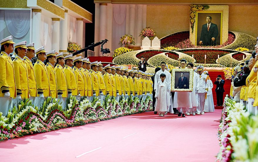 Members of the Moon family, including grandson Shin Jun (left) and Kwon Jin Moon, a son of the Rev. Sun Myung Moon, carry portrait of the Unification Church leader after the ascension ceremony Saturday for the reverend, who died Sept. 2 in Gapyeong, Korea. Lining the walkway are members of second-generation church families. (Barbara L. Salisbury/The Washington Times)