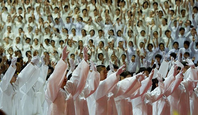 Family members and others who filled the 14,000-seat arena for Rev. Moon’s services raise their arms in the three cheers of EokMansei, a traditional Korean gesture. Church officials estimate some 35,000 people made the trip to Gapyeong. (Barbara L. Salisbury/The Washington Times)