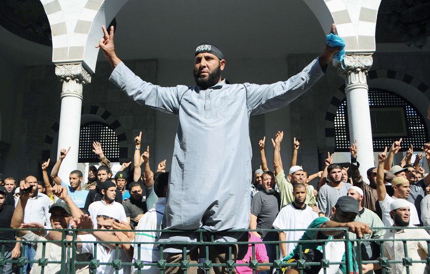 Associated Press photographs
Tunisian activists protest outside the El Fateh mosque in Tunis, surrounded by police, in support of a hard-line Muslim known as Abu Yadh, on Monday. Police surrounded the mosque but did not enter.