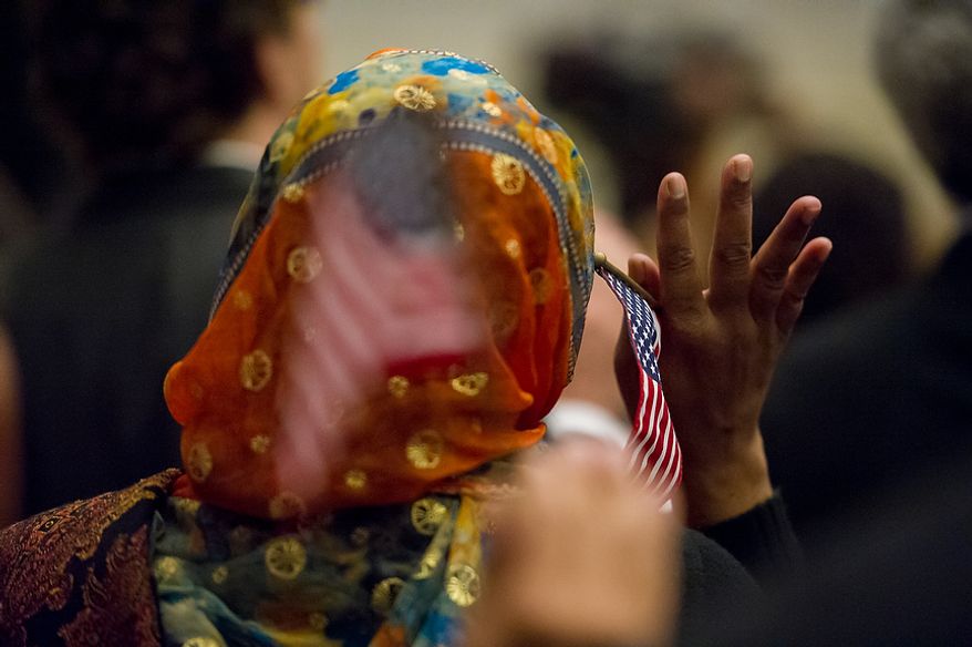 A petitioner holds an American flag in her hand as she and 224 others were sworn in as U.S. citizens on Sept. 17, 2012, at the National Archives Building in Washington, during a naturalization ceremony to commemorate the 225th anniversary of the signing of the U.S. Constitution. (Andrew Harnik/The Washington Times)