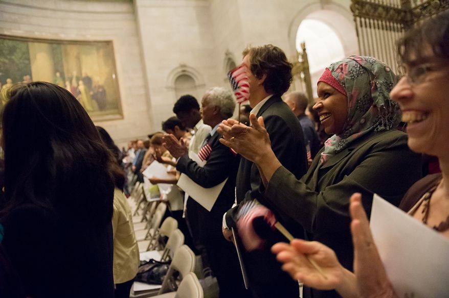 Mahjouba Elhaloui (second from right), originally from Morocco, and Natalie Donn White (right), originally from Canada, applaud with 223 other newly sworn-in U.S. citizens on Sept. 17, 2012, at the National Archives Building in Washington. The ceremony commemorated the 225th anniversary of the signing of the U.S. Constitution. (Andrew Harnik/The Washington Times)