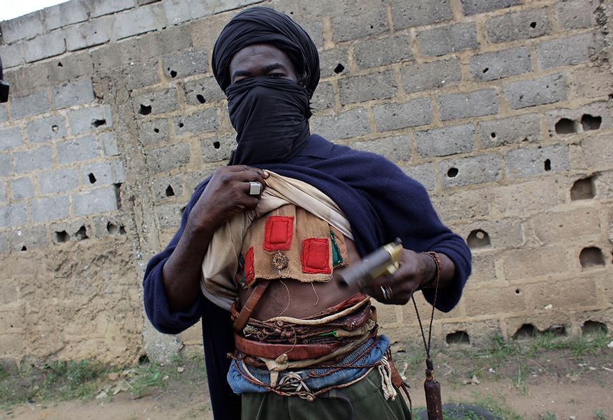 A fighter opposed to Ivorian strongman Laurent Gbagbo's bid to cling to power displays the amulets he wears to protect himself from enemy fire, in the Abobo district of Abidjan, Ivory Coast, on Saturday, March 12, 2011. (AP Photo/Rebecca Blackwell)