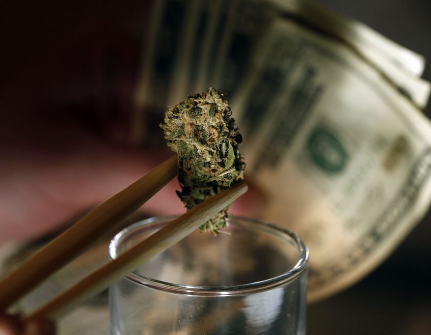 ** FILE ** A caregiver picks out a marijuana bud for a patient at a marijuana dispensary in Denver on Tuesday, Sept. 18, 2012. (AP Photo/Ed Andrieski)