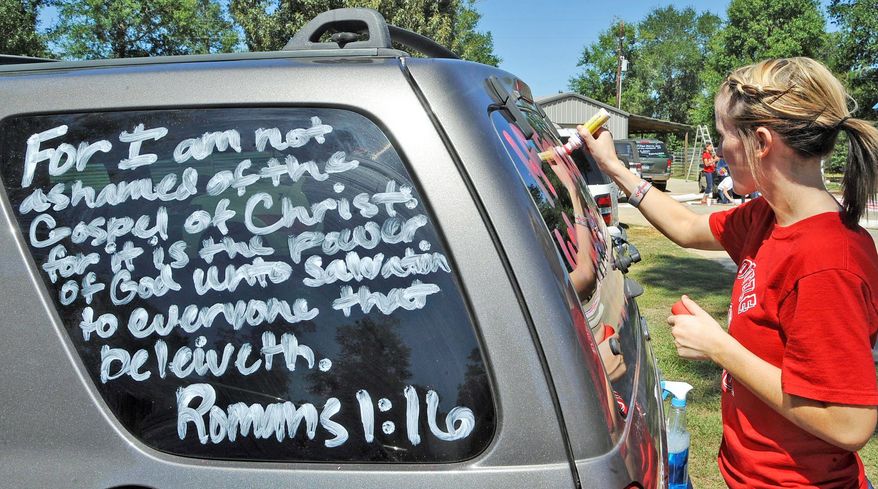 Kountze High School cheerleader Brooke Coates writes Scripture verses on a vehicle. The southeast Texas community is backing cheerleaders after they were told not to use Scripture verses on their banners at football games. The court has intervened in the issue of religion in public schools. (Associated Press)