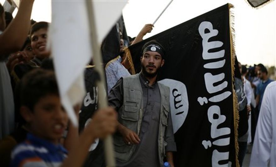 ** FILE ** A Libyan follower of Ansar al-Shariah Brigades stands in front a black flag, with Arabic writing that reads, "there is no God but Allah and Muhammad is his messenger," during a protest in front of the Tibesti Hotel, in Benghazi, Libya, Sept. 14, 2012. (AP Photo/Mohammad Hannon)