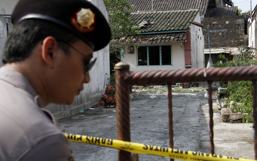 An Indonesian police officer stands guard outside the house of a suspected militant after a police raid in Solo, Indonesia, on Saturday, Sept. 22, 2012. An elite Indonesian anti-terror squad has arrested 10 Islamic militants and seized a dozen homemade bombs from a group suspected of planning suicide attacks against security forces and the government, police said Sunday. (AP Photo/A.K. Hendratmo)