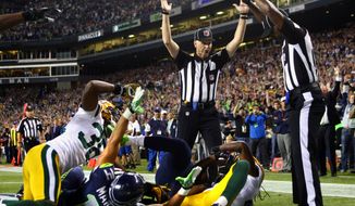 Officials signal after Seattle Seahawks wide receiver Golden Tate pulled in a last-second pass for a touchdown from quarterback Russell Wilson to defeat the Green Bay Packers 14-12 in an NFL football game, Monday, Sept. 24, 2012, in Seattle. The touchdown call stood after review. (AP Photo/seattlepi.com, Joshua Trujillo)  MAGS OUT; NO SALES; SEATTLE TIMES OUT; TV OUT; MANDATORY CREDIT