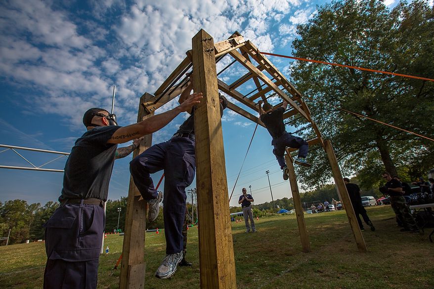 Metro Transit Officers, from Washington D.C., use upper body strength to cross the monkey bars while wearing gas masks at the Iron Team Endurance Competition in Laurel, MD., Wednesday, September 26, 2012. The competition is hosted by the Prince George's County Police where teams from all over the east coast, including the Marines, compete in a grueling physical endurance challenge.(Andrew S. Geraci/The Washington Times)