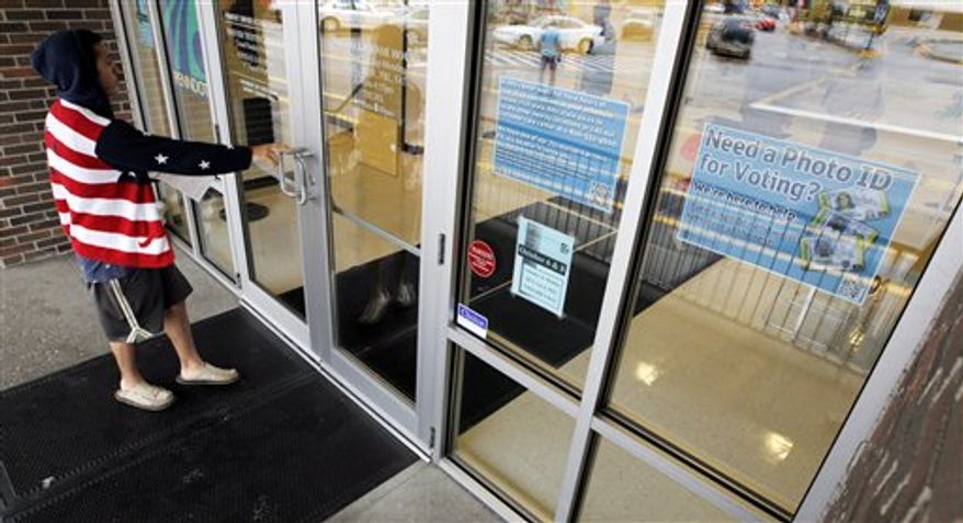 ** FILE ** A man heads into the the Penndot Drivers License Center in Butler, Pa., on Wednesday, Sept. 26, 2012, near a sign telling of the requirement for voters to show an acceptable photo ID to vote. (AP Photo/Keith Srakocic)