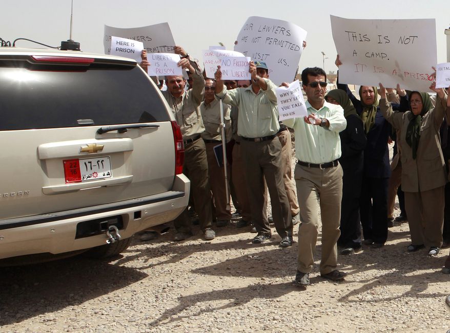 **FILE** Members of the Mujahedeen-e-Khalq organization chant slogans and hold banners during a tour organized by the Iraqi government for foreign diplomats in Baghdad on Sept. 11, 2012. (Associated Press)