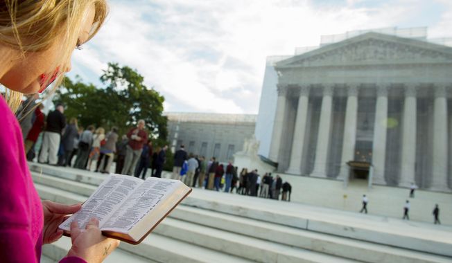 A woman holds a Bible while standing in silent prayer on the steps of the U.S. Supreme Court on Oct. 1, 2012, before the justices return to the bench for another term. (Rod Lamkey Jr./The Washington Times)