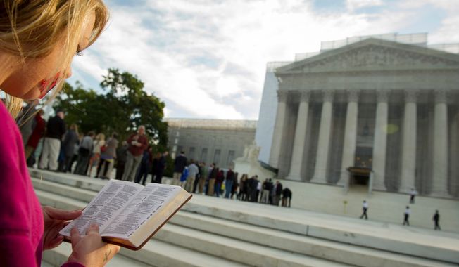 ** FILE ** A woman holds a Bible while standing in silent prayer on the steps of the Supreme Court on Oct. 1, 2012, before the justices return to the bench for another term. (Rod Lamkey Jr./The Washington Times)