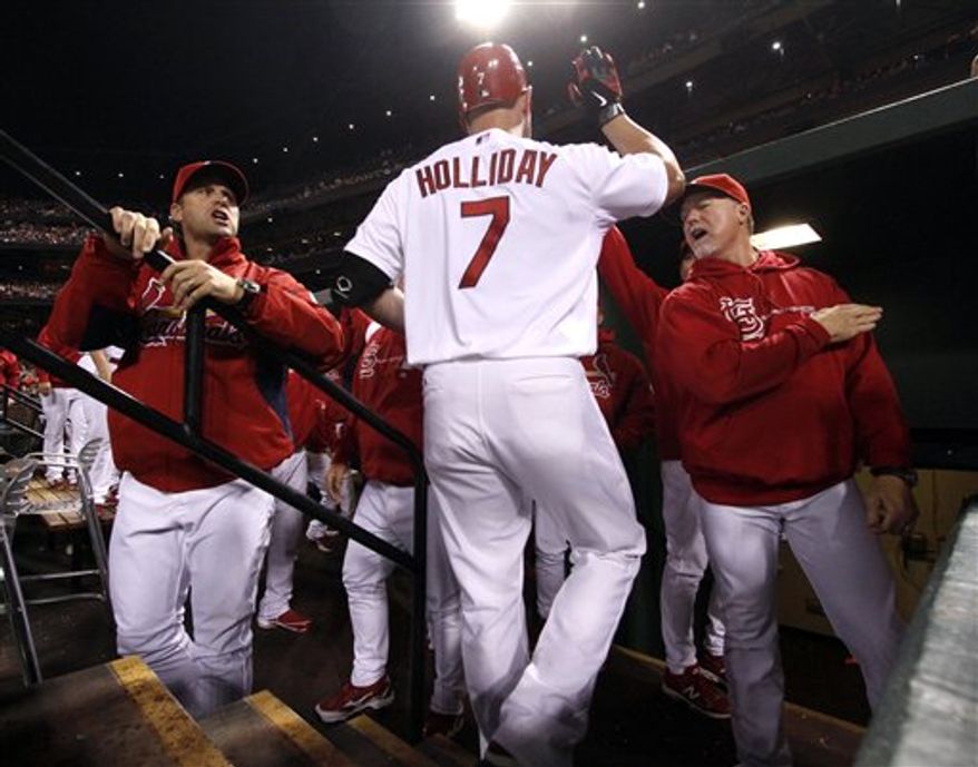 St. Louis Cardinals' Matt Holliday is congratulated by manager Mike Matheny, left, and hitting coach Mark McGwire, right, after driving in a run with a sacrifice fly during the first inning of a baseball game against the Cincinnati Reds on Tuesday, Oct. 2, 2012, in St. Louis. (AP Photo/St. Louis Post-Dispatch, Chris Lee)