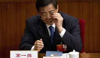 ** FILE ** Then-Chongqing Party Secretary Bo Xilai puts on his glasses during a plenary session of the National People&#39;s Congress at the Great Hall of the People in Beijing on Monday, March 11, 2012. (AP Photo/Andy Wong)